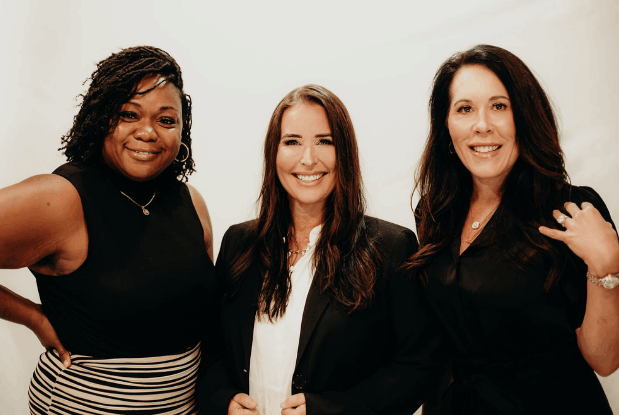 Three women from the True Aesthetics & Wellness team standing together and smiling